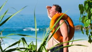 Orange Safety Ring on Man Shoulder Near Body of Water