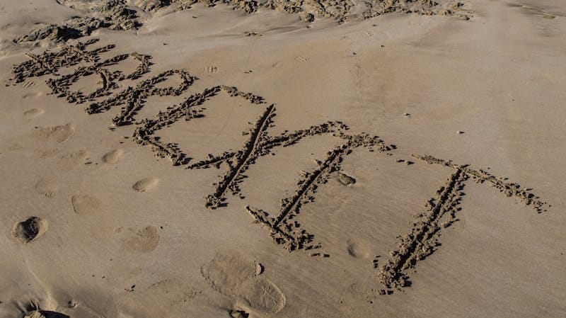 'Brexit' inscribed on sandy beach with footprints around it.