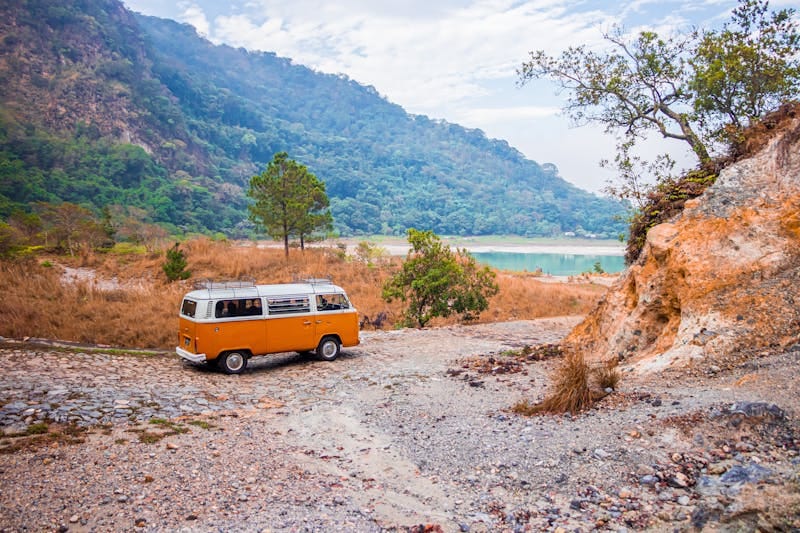 Explore El Salvador's natural beauty with a classic VW bus by a serene lakeside view.