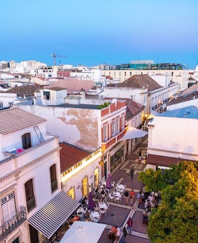 A lively evening scene in Faro, Portugal featuring bustling streets and outdoor cafes.