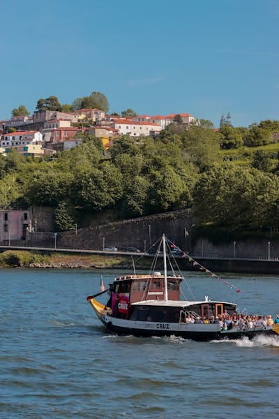 Tourist boat cruising on Douro River with Porto's hillside in view.