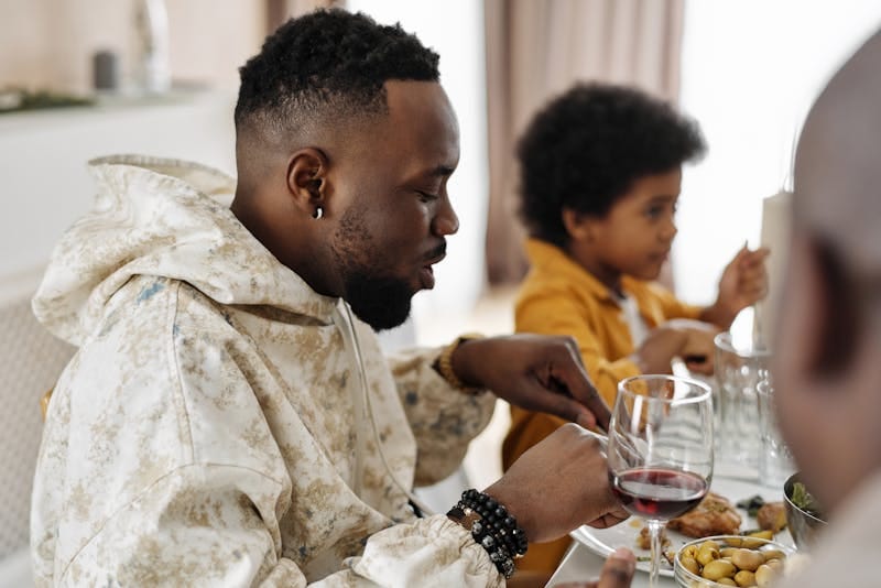 Adults and children enjoying a meal together indoors, depicting family bonding and diversity.