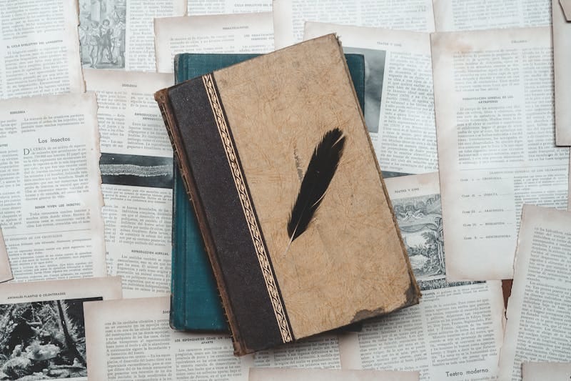 A classic setup with vintage books and a black feather on aged paper, perfect for historical or educational themes.
