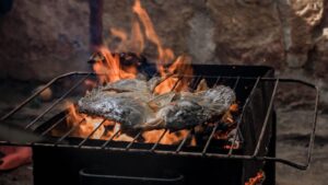 A grilled fish cooking over an open flame, showcasing traditional barbecue style.