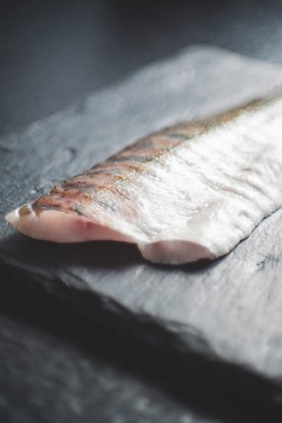 Close-up of a fresh salmon fillet placed on a dark slate surface, capturing its natural texture.